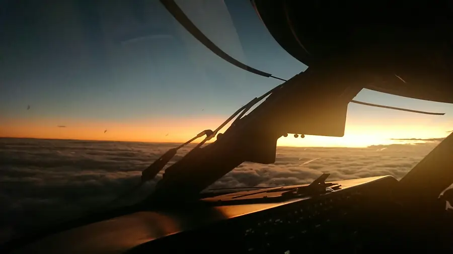 Sunrise over a sea of cloud, seen from an airliner cockpit