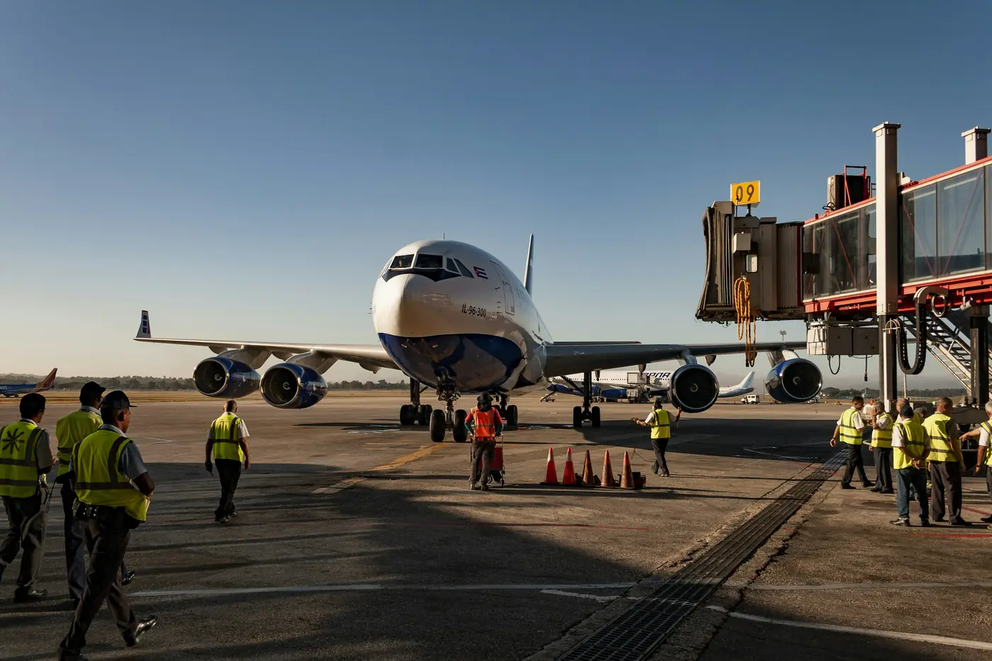 Ground crew in high-visibility vests walking out to a wide-body aircraft at the gate