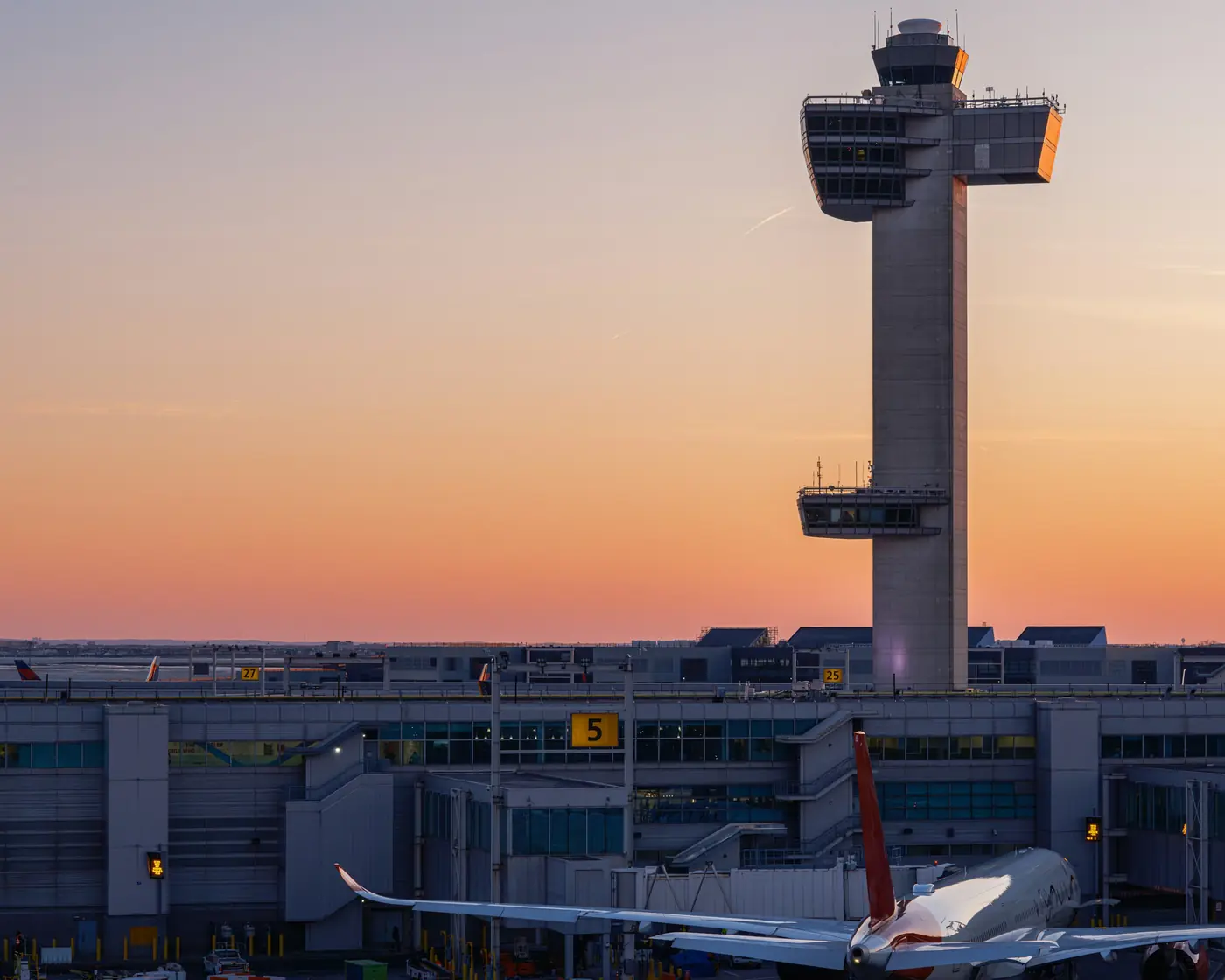 Air traffic control tower against a sunset sky above the terminal