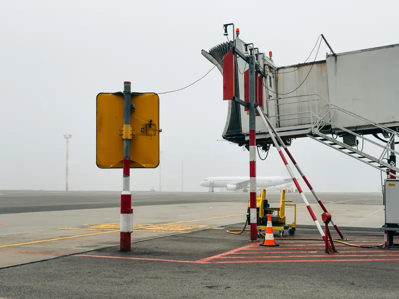 Jet bridge and yellow stand sign on a quiet, misty apron